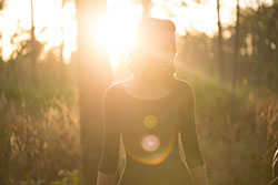 Photo: Woman in forest with sun behind her